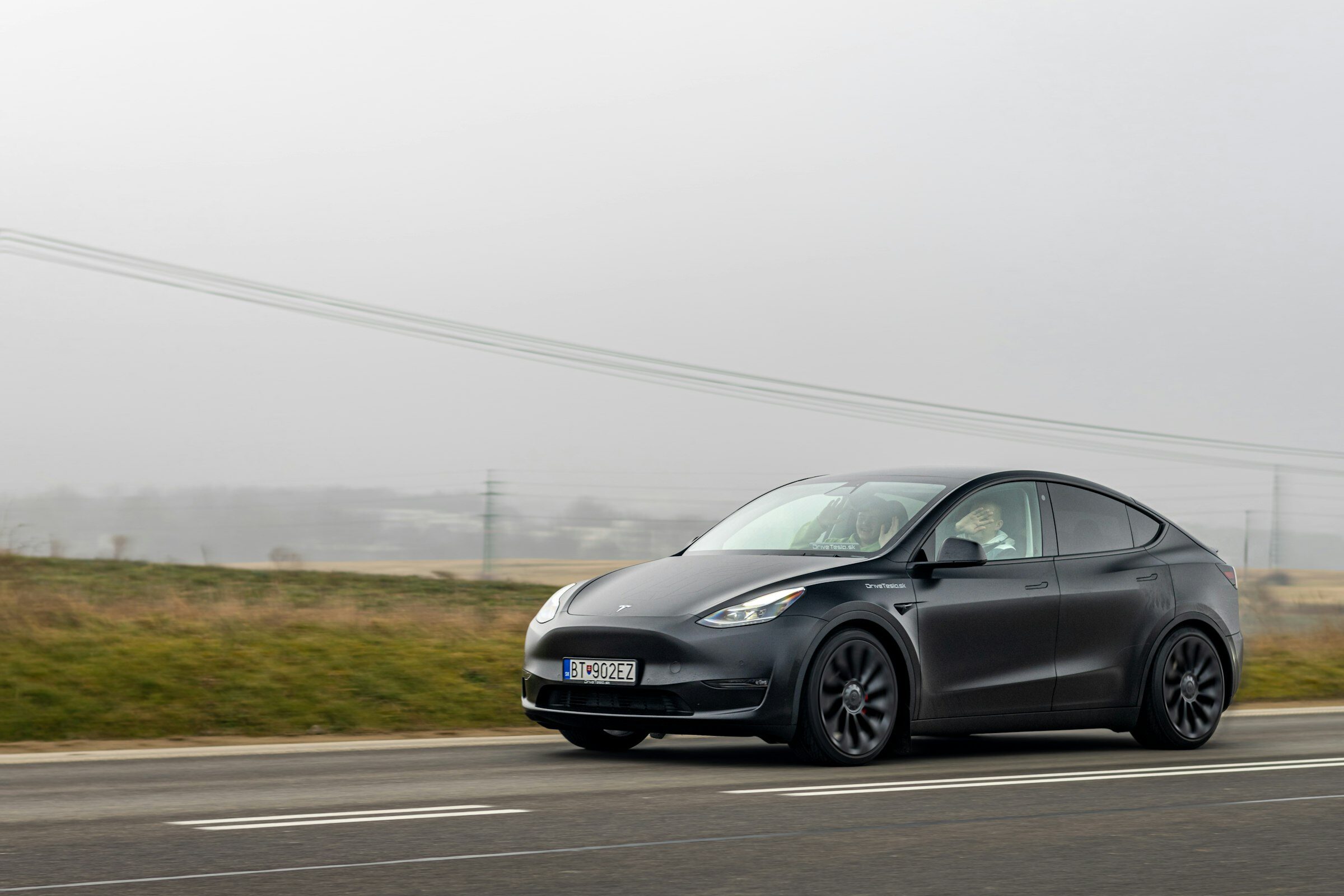 A black Tesla Model Y travelling an open road.