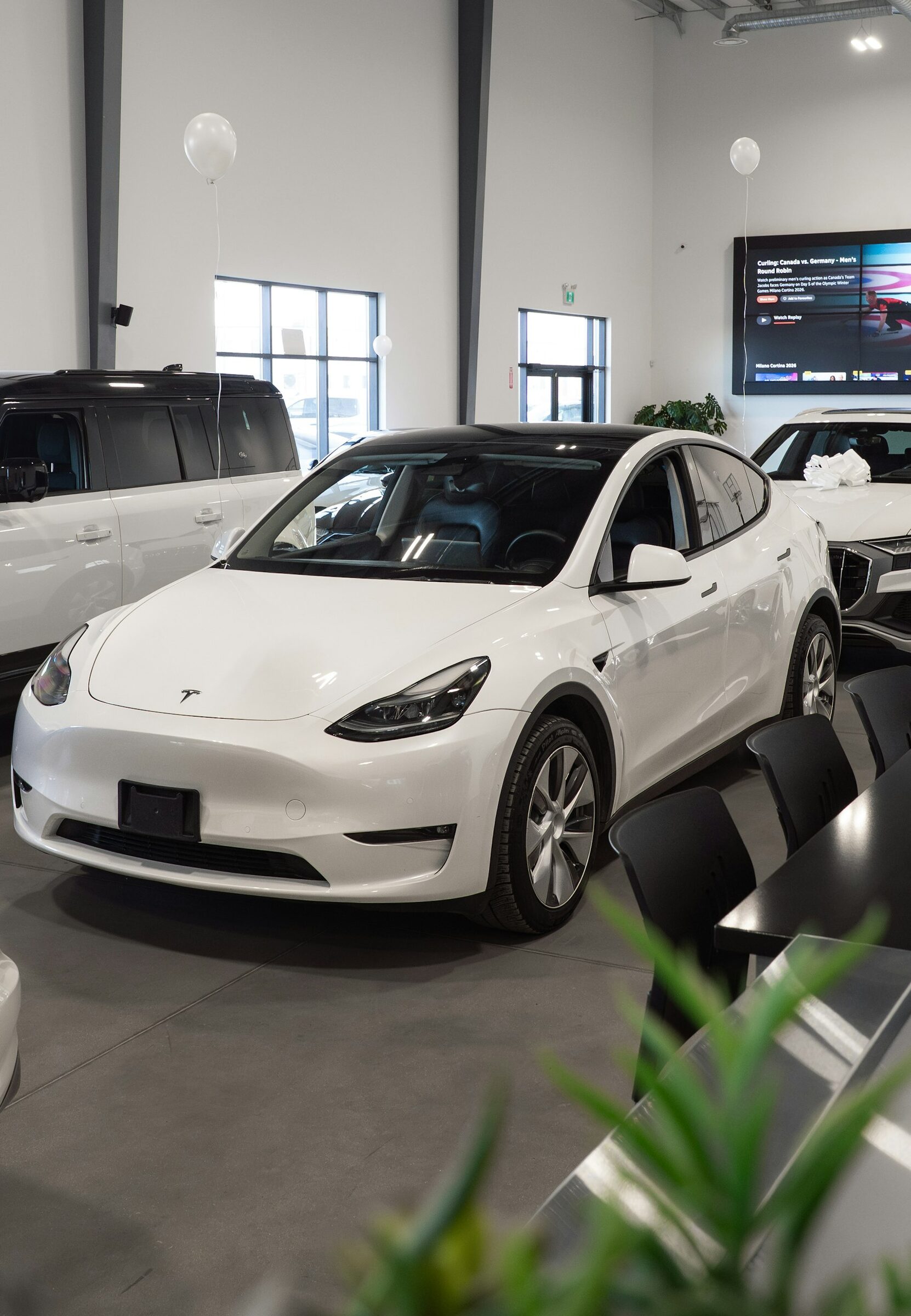A white Tesla Model Y in a showroom, the working vehicle.